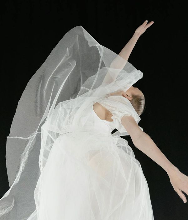Woman performing a fluid, graceful movement in a bright, airy space.